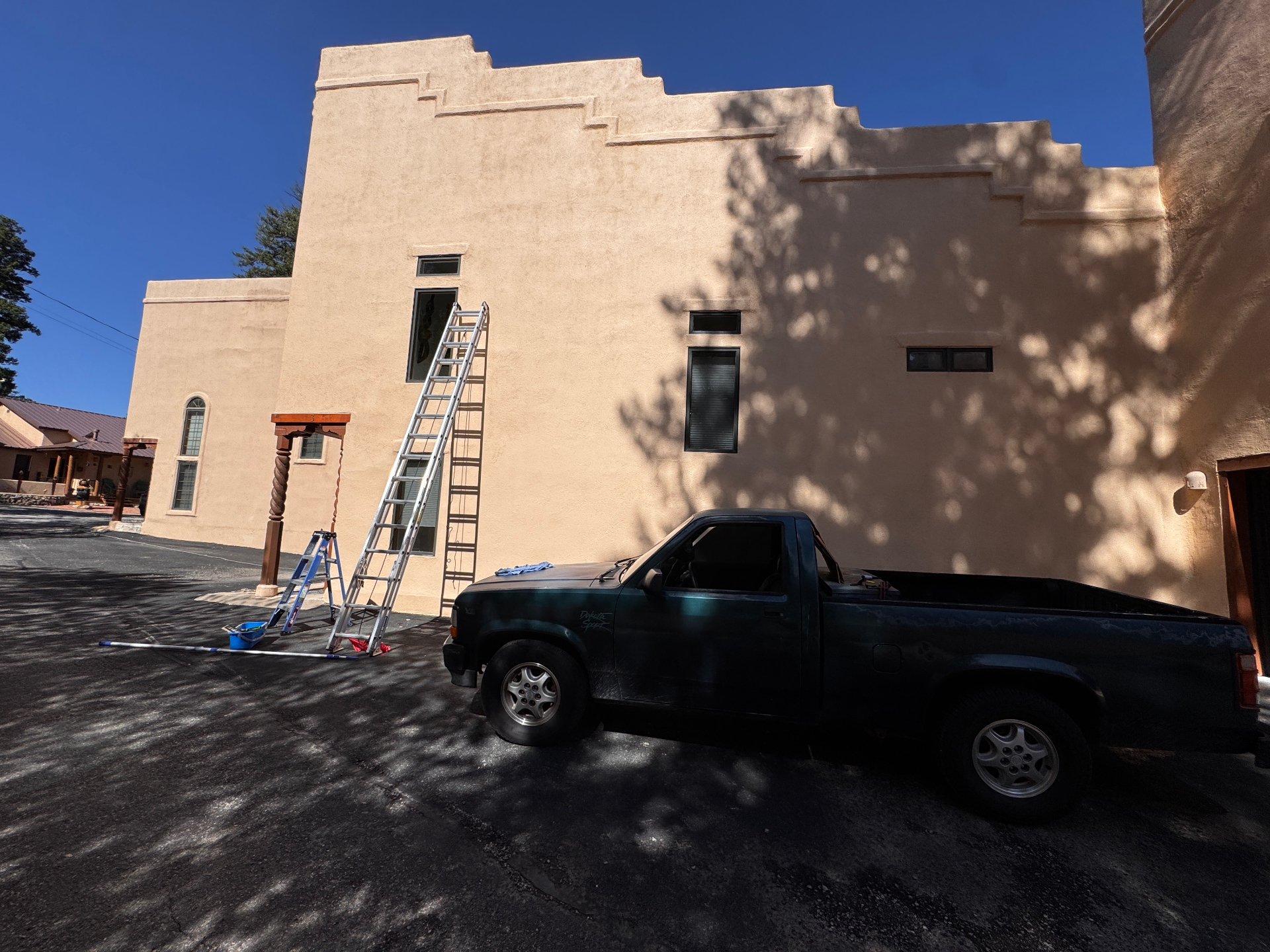 Extension ladder set up against a tall stucco building for a two-story window cleaning job